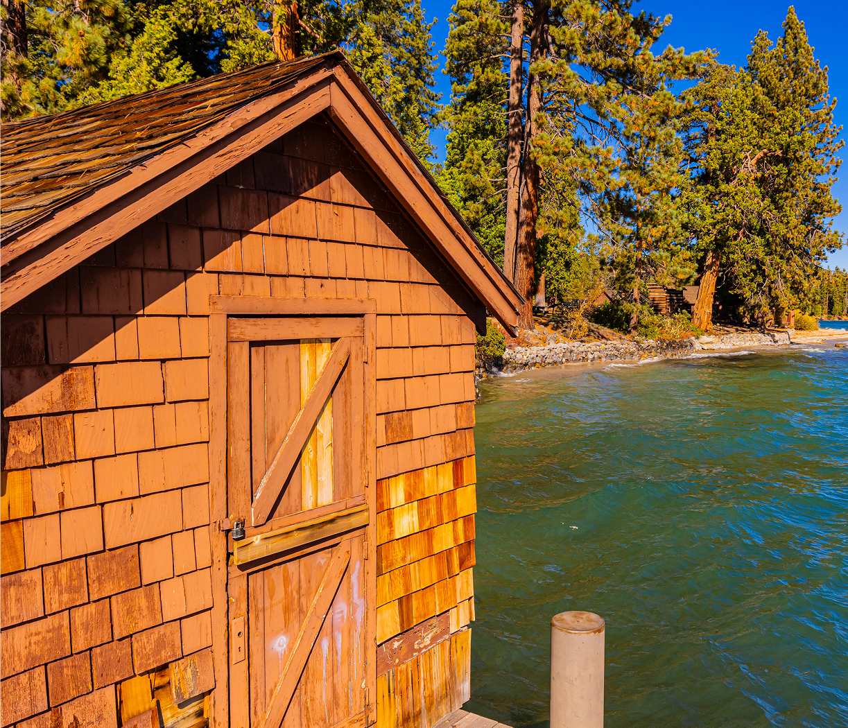 Sunlit wooden boathouse on pine-lined lake