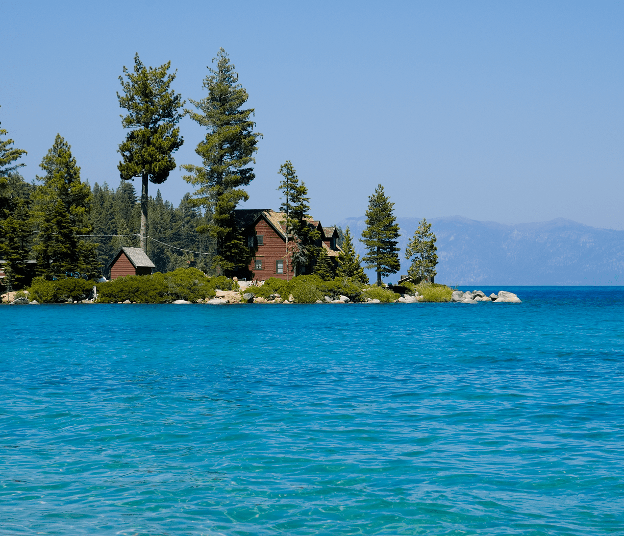 Cabins on forested island by turquoise lake