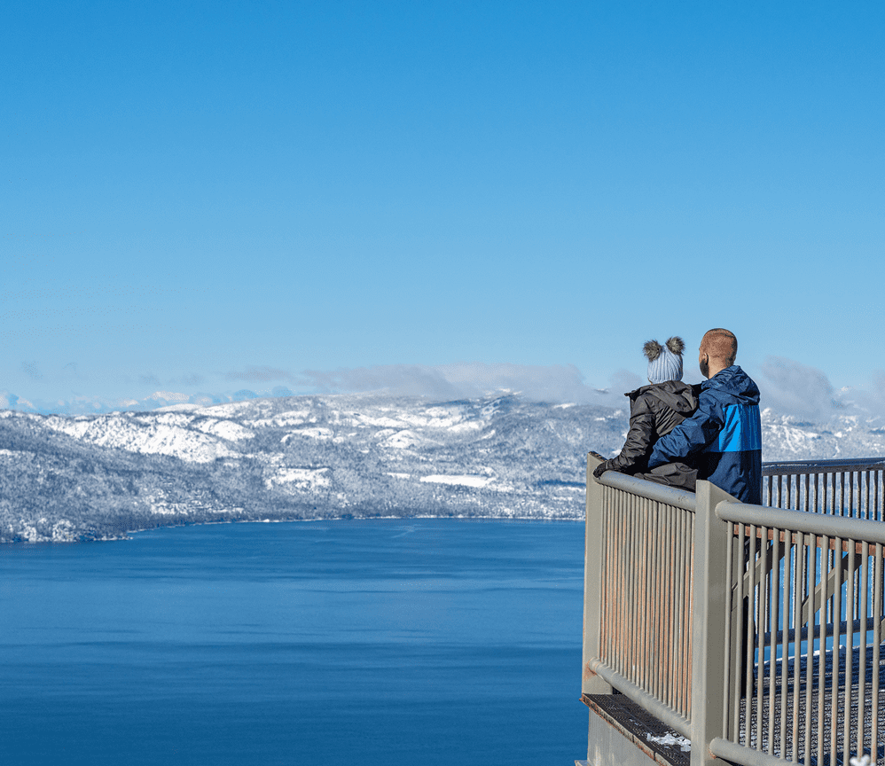 Two people on platform overlooking snowy lake