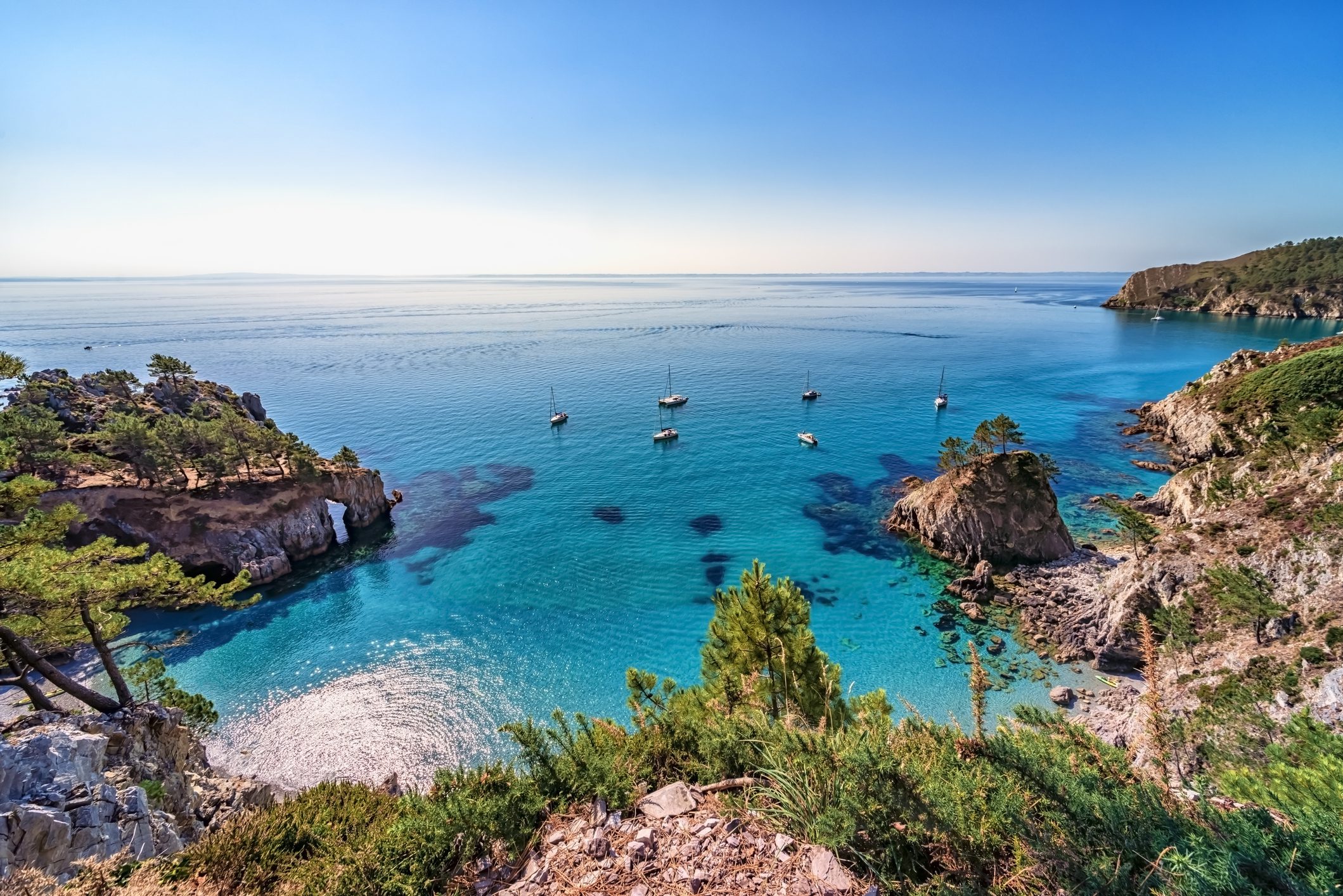 Secluded turquoise bay with sailboats and cliffs