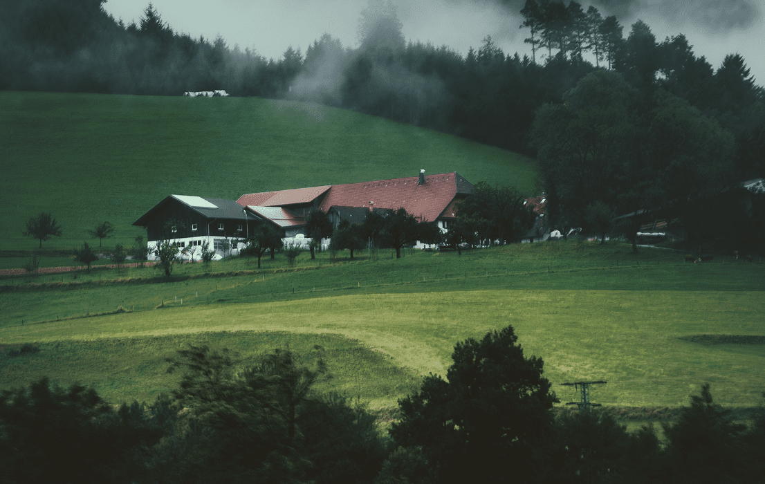Farmhouse with red roof in foggy green hills