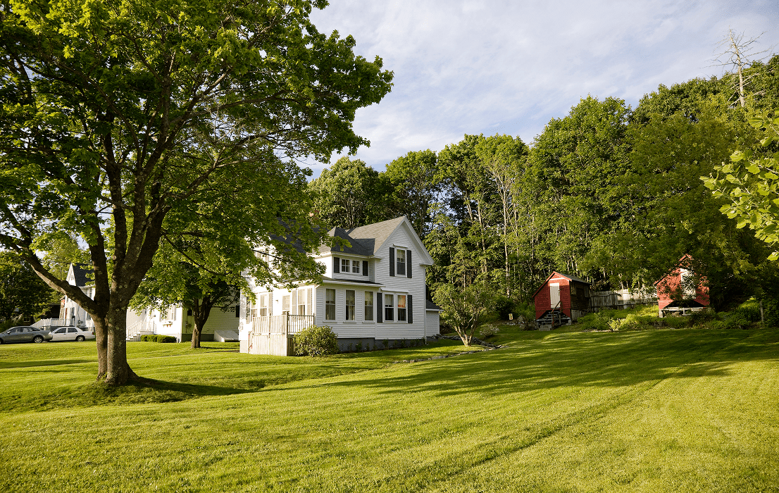 White farmhouse with green lawn and barn